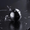 A close-up shot of a polished, silver metal fidget spinner resting on a dark marble surface.