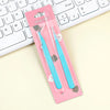A pink packaging box holds a pair of blue precision stainless steel tweezers for nail art and makeup, resting on a white lapt