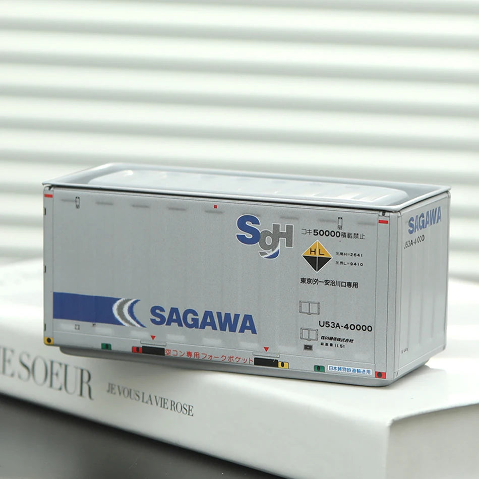 A silver industrial storage box labeled SAGAWA with a blue and white logo resting on a white book.