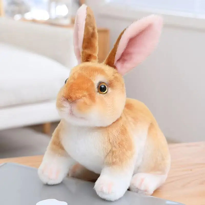 A cute, fluffy orange rabbit plush toy with pink inner ears sitting on a wooden surface.