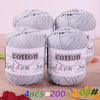 Four skeins of gray cotton knitting yarn for crochet and handmade projects displayed on a wooden surface.