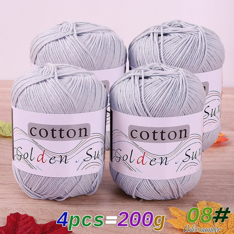 Four skeins of gray cotton knitting yarn for crochet and handmade projects displayed on a wooden surface.