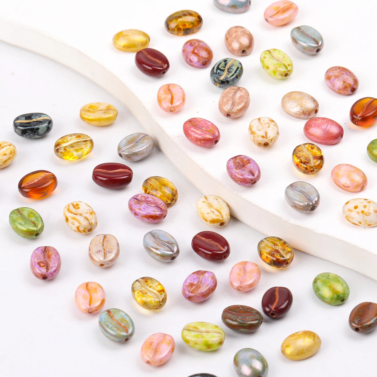 A collection of colorful Czech glass coffee bean beads for jewelry making, displayed on a white background.