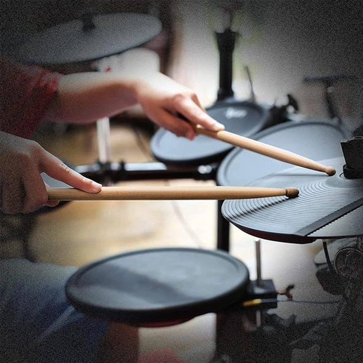 A person is holding a wooden maple drumstick above a black cooking pan in a kitchen setting.