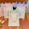 A display of mermaid princess pearl butterfly hair clips in various shades of pink and blue on a brown surface.