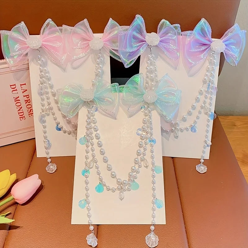 A display of mermaid princess pearl butterfly hair clips in various shades of pink and blue on a brown surface.