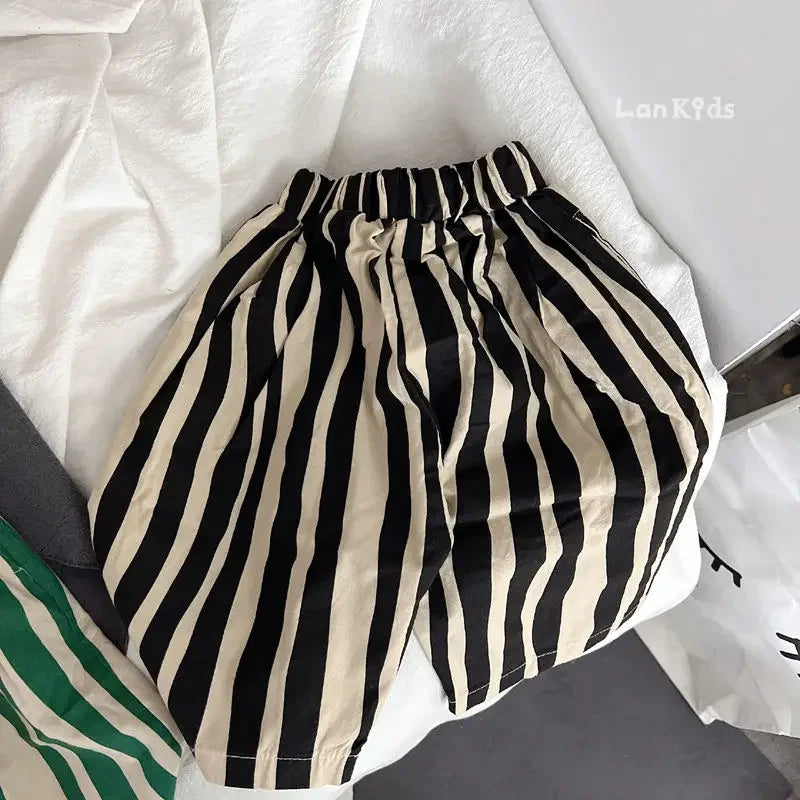 A pair of black and beige striped cotton harem pants for kids lying on a white surface.
