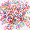 A colorful pile of polymer clay flower charms in various shades of pink, blue, and yellow.