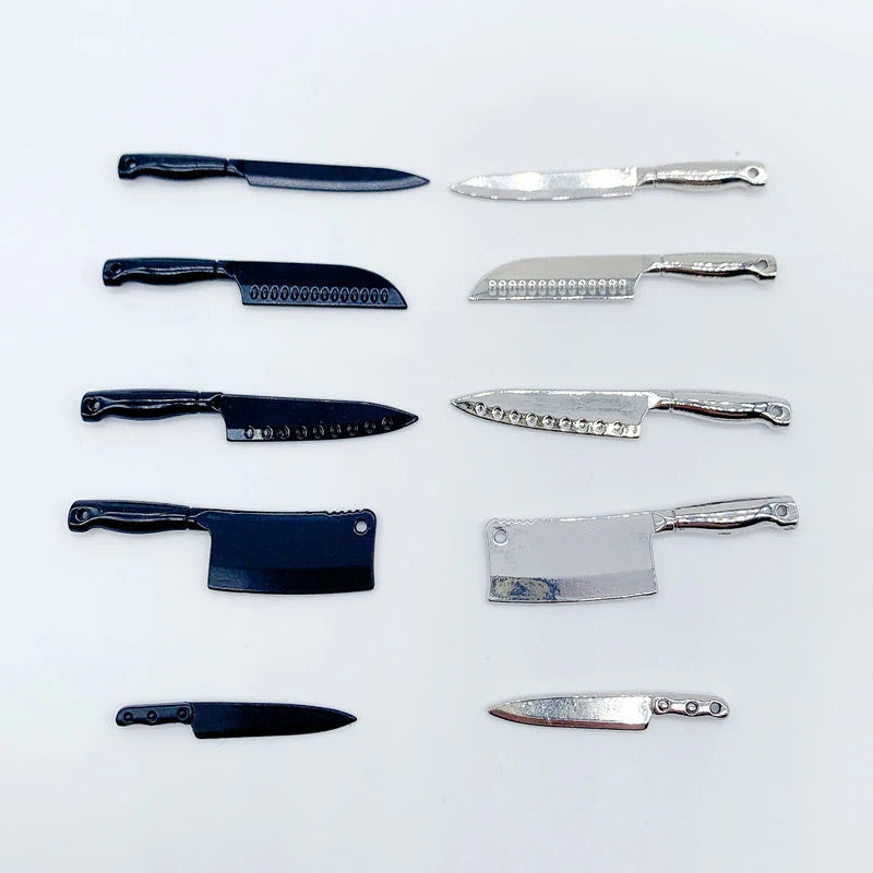 A collection of miniature metal kitchen knives in various sizes and finishes for a dollhouse.