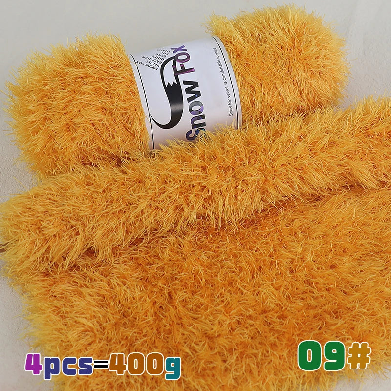 A pile of bright orange fluffy faux fur yarn with a label showing Snow Fox branding.