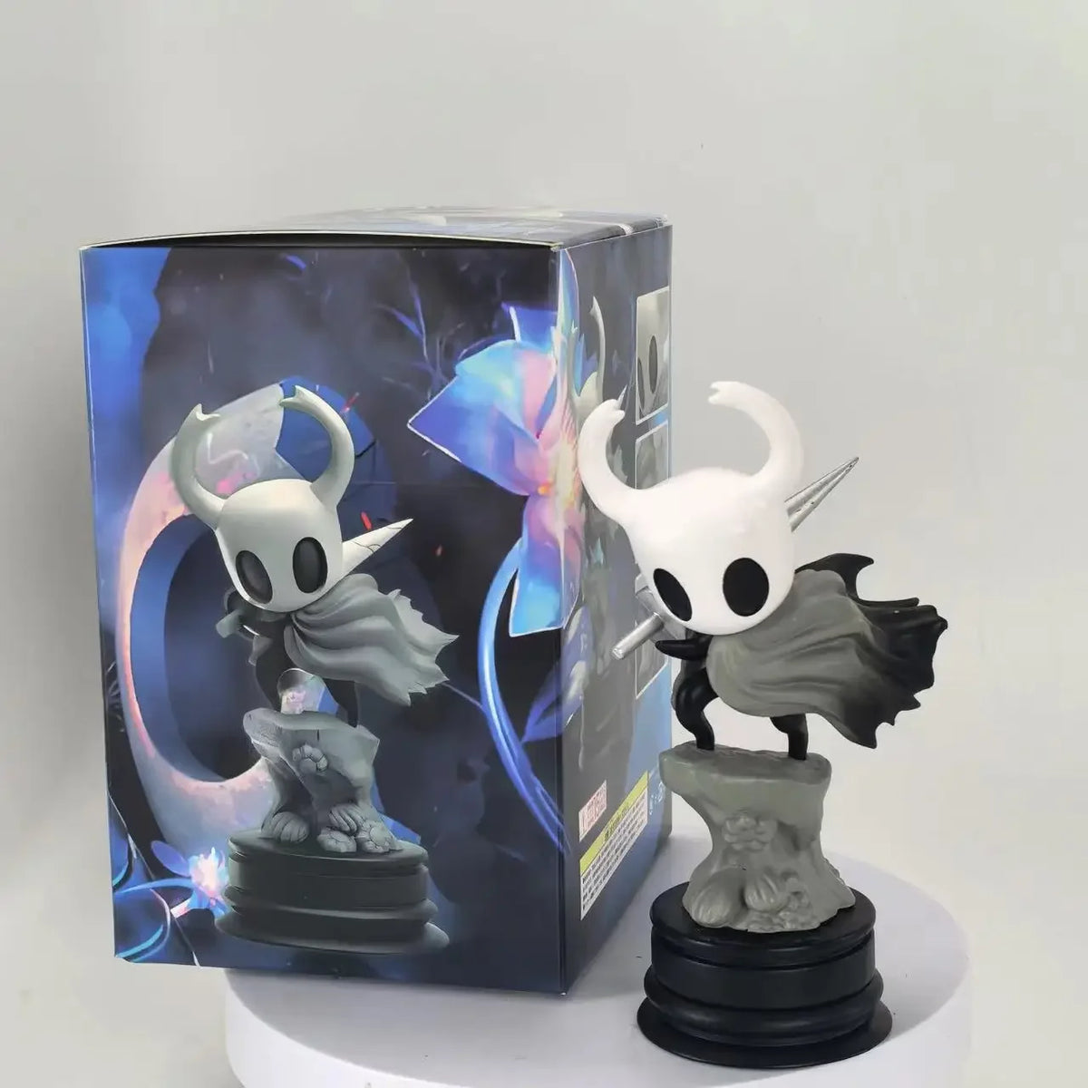 A handcrafted PVC figure of the Hollow Knight Little Knight in a black and white design standing on a circular base.