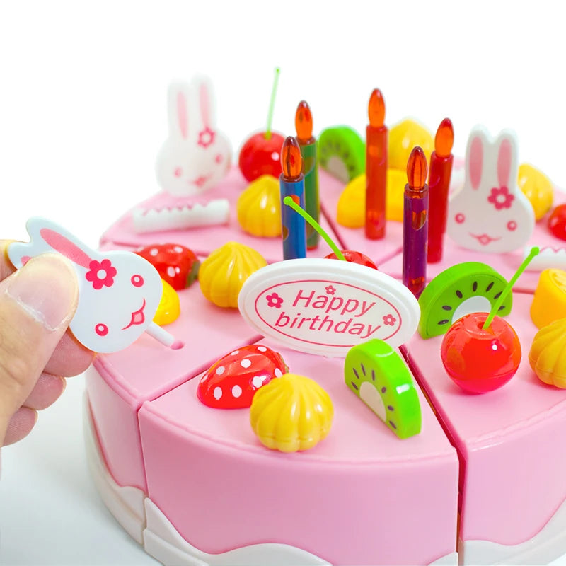 A pink pretend play birthday cake set featuring colorful candies, candles, and decorative elements for children.