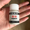 A small white bottle of water marbling paint material labeled in Chinese characters is held in a person's hand.