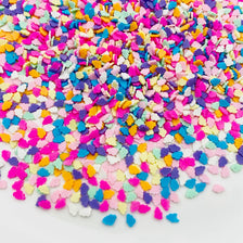 A pile of colorful polymer clay star and heart sprinkles in various shades of pink, purple, blue, yellow, and white.