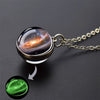 A pendant necklace featuring a glass sphere with an image of a nebula and a glowing green orb.