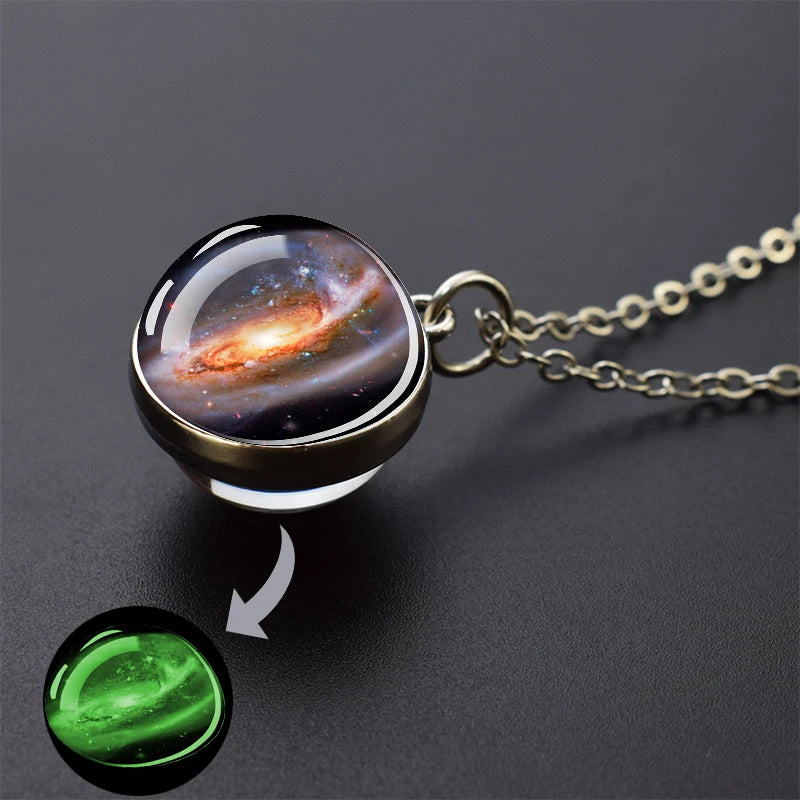 A pendant necklace featuring a glass sphere with an image of a nebula and a glowing green orb.