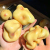A hand holds several yellow, squishy potato-shaped stress balls against a dark background.