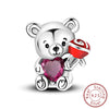 A silver teddy bear charm holding a red heart-shaped bead for a bracelet collection.