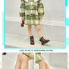 A young girl models a plaid coat with a cream collar and ankle boots.