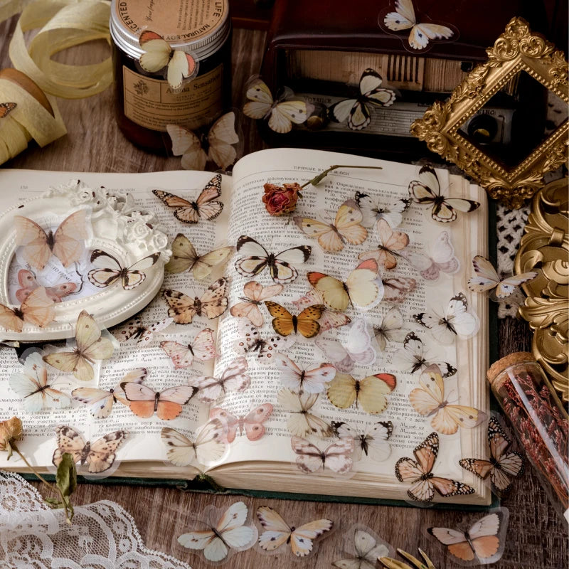 A collection of delicate butterfly stickers on a page of an open book with floral accents.