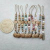A string of personalized wooden baby pacifier clips featuring silicone beads in various natural and pastel colors.