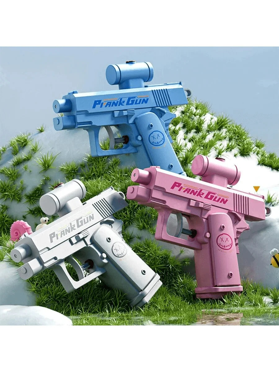 A pink and blue prank gun toy is shown lying on green grass with foliage in the background.