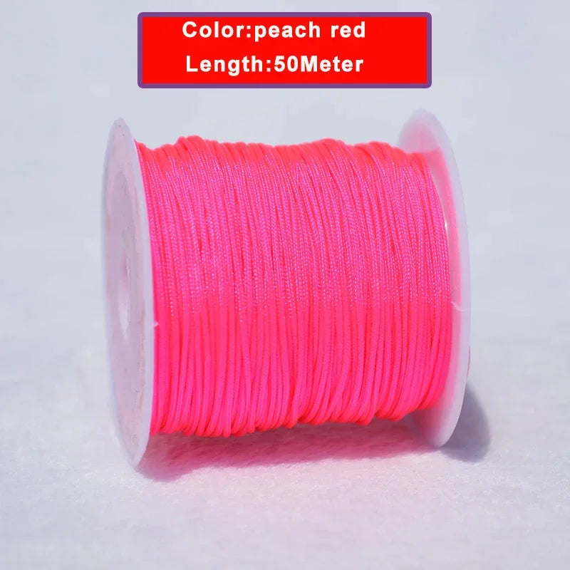 A spool of peach red, 50-meter long nylon knotting cord for jewelry making.