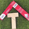 A wooden tangram puzzle shaped like the letter T is placed on green grass next to a red and white card.