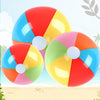 A set of six colorful rainbow inflatable beach balls floating above a sandy beach background.