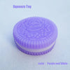 A purple and white biscuit-shaped squeeze toy with a textured top and smooth bottom.