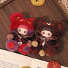 A plush charm of a bear character with red and purple fur and features, displayed on a wooden surface.