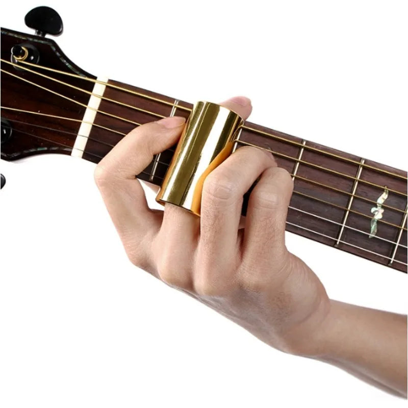 A hand is pressing a gold-colored slide bar onto the fretboard of a guitar.