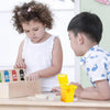 Two children are playing with a mini recycling truck toy set on a table.