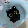 A black cat plush cushion with yellow eyes is attached to a light blue fabric bag.