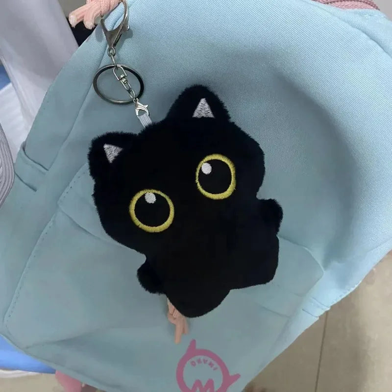A black cat plush cushion with yellow eyes is attached to a light blue fabric bag.