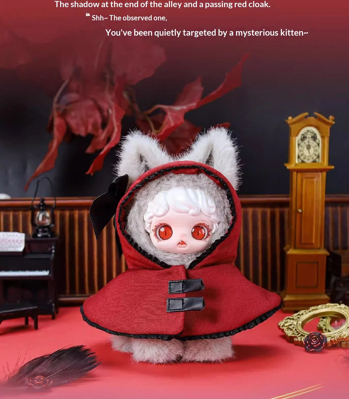 A fluffy red hooded plush doll with white hair and large eyes sits on a red surface.