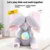 Peluche d'éléphant gris avec des oreilles roses assis sur un tapis blanc.