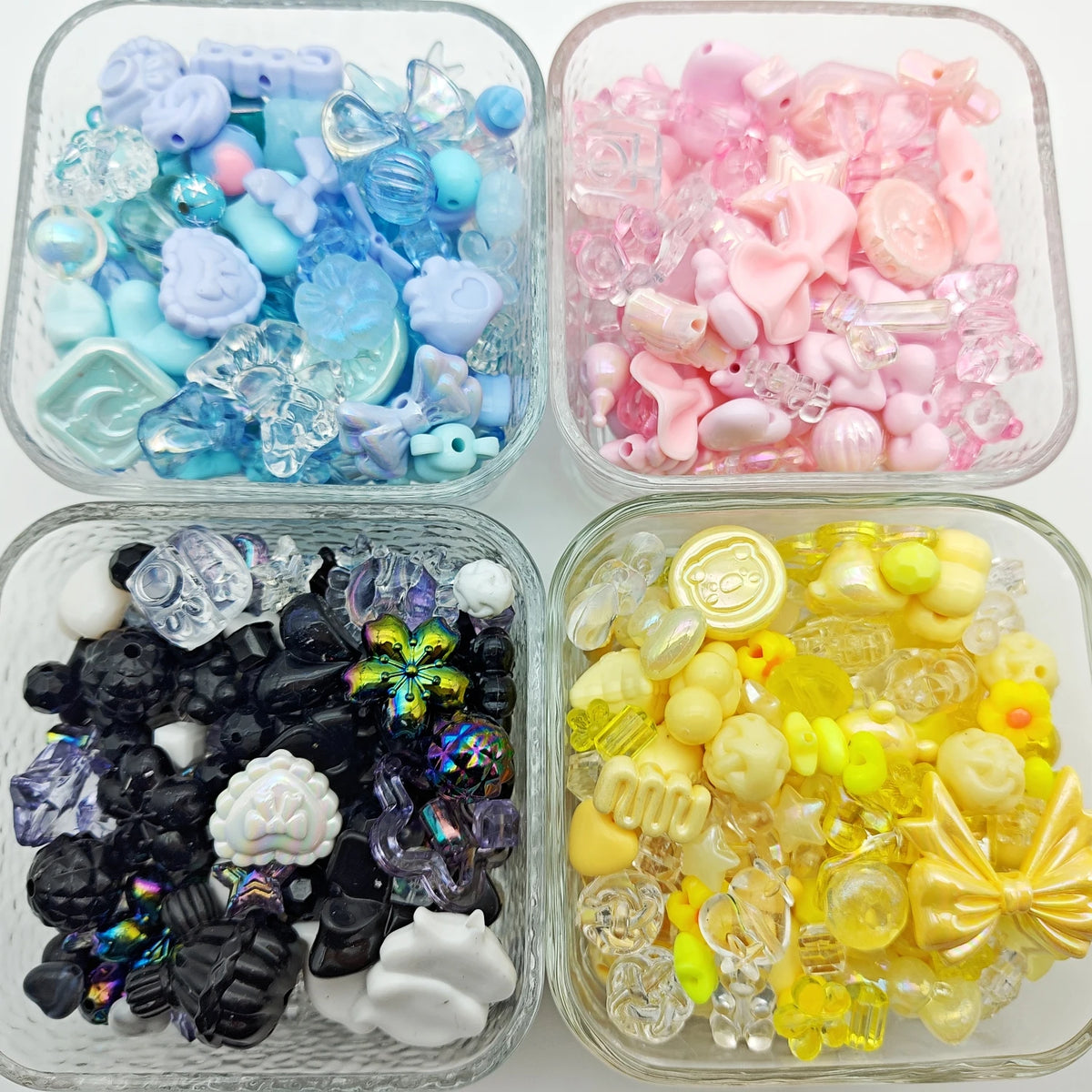 Clear containers filled with various mixed acrylic loose beads in shades of blue, pink, and yellow for jewelry making