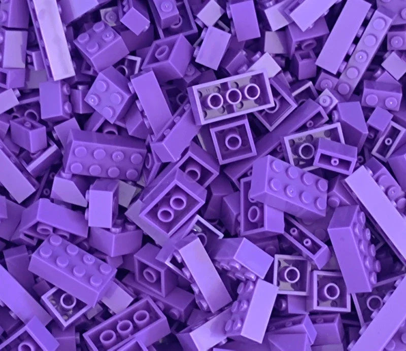 A close-up view of many small purple plastic building blocks scattered on a surface.