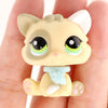 A small, light yellow miniature cat figure with white ears and blue accents is held in a person's hand.