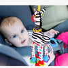 Ein Baby hält ein Plüsch-Giraffe-Zebra-Handgelenkspielzeug.