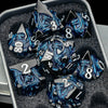 A set of black and blue dragon-themed metal dice displayed in a gray container.