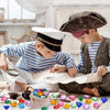 A young boy is crafting with colorful acrylic gemstones and other treasures on a piece of paper.