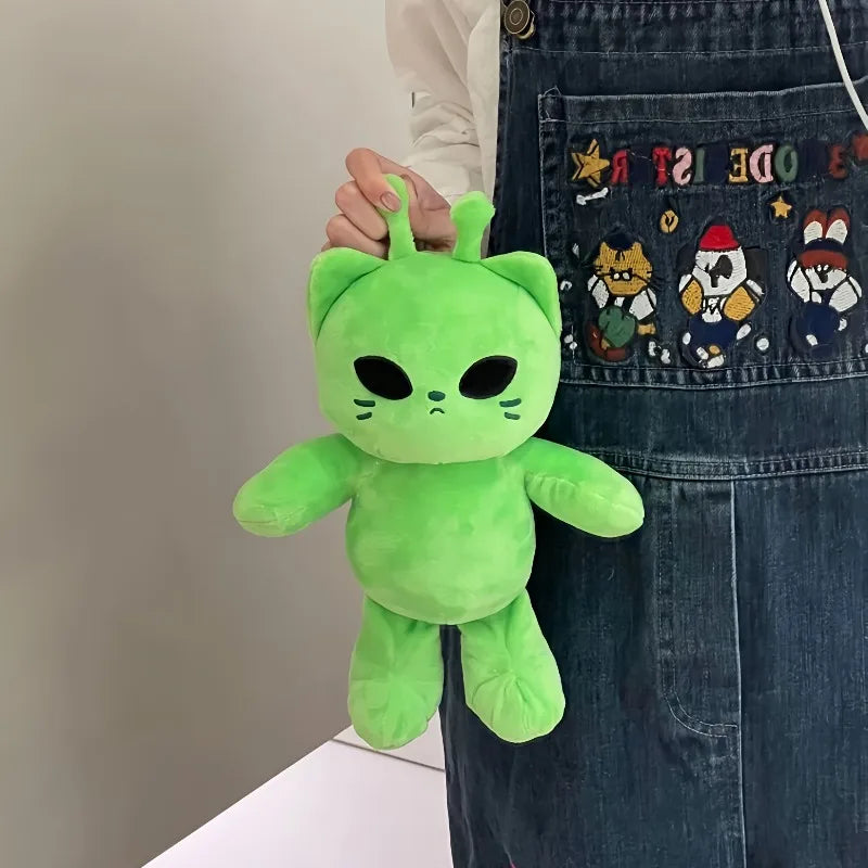 A bright green plush toy shaped like an alien cat is being held by a person wearing a denim apron.