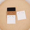 Three stacked square cards in black, brown, and white are displayed on a cork board.