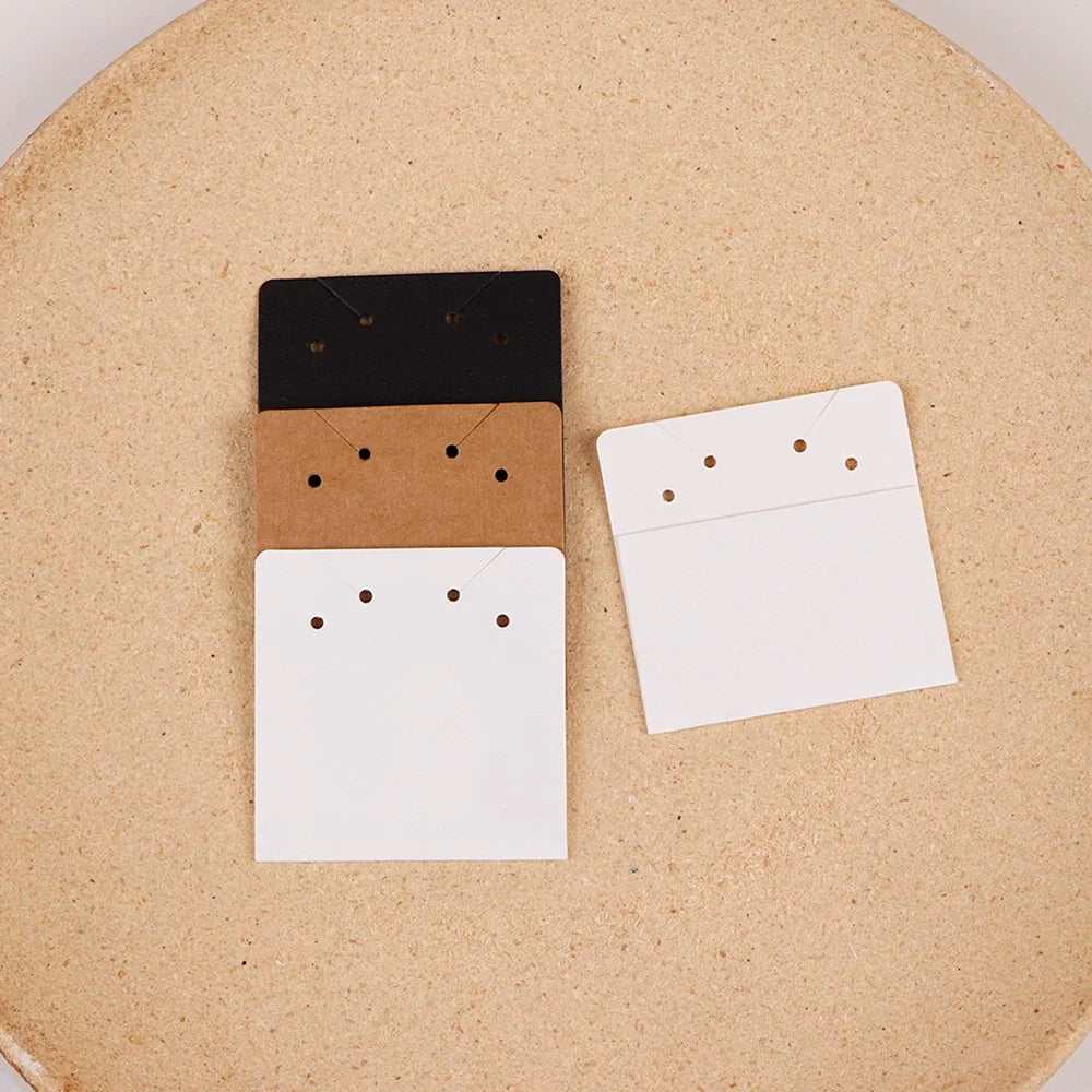 Three stacked square cards in black, brown, and white are displayed on a cork board.