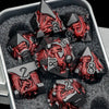 A set of black metal dice featuring a red dragon design is displayed in a silver container.
