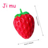 A bright red strawberry squishy stress ball with a green stem and leaves.