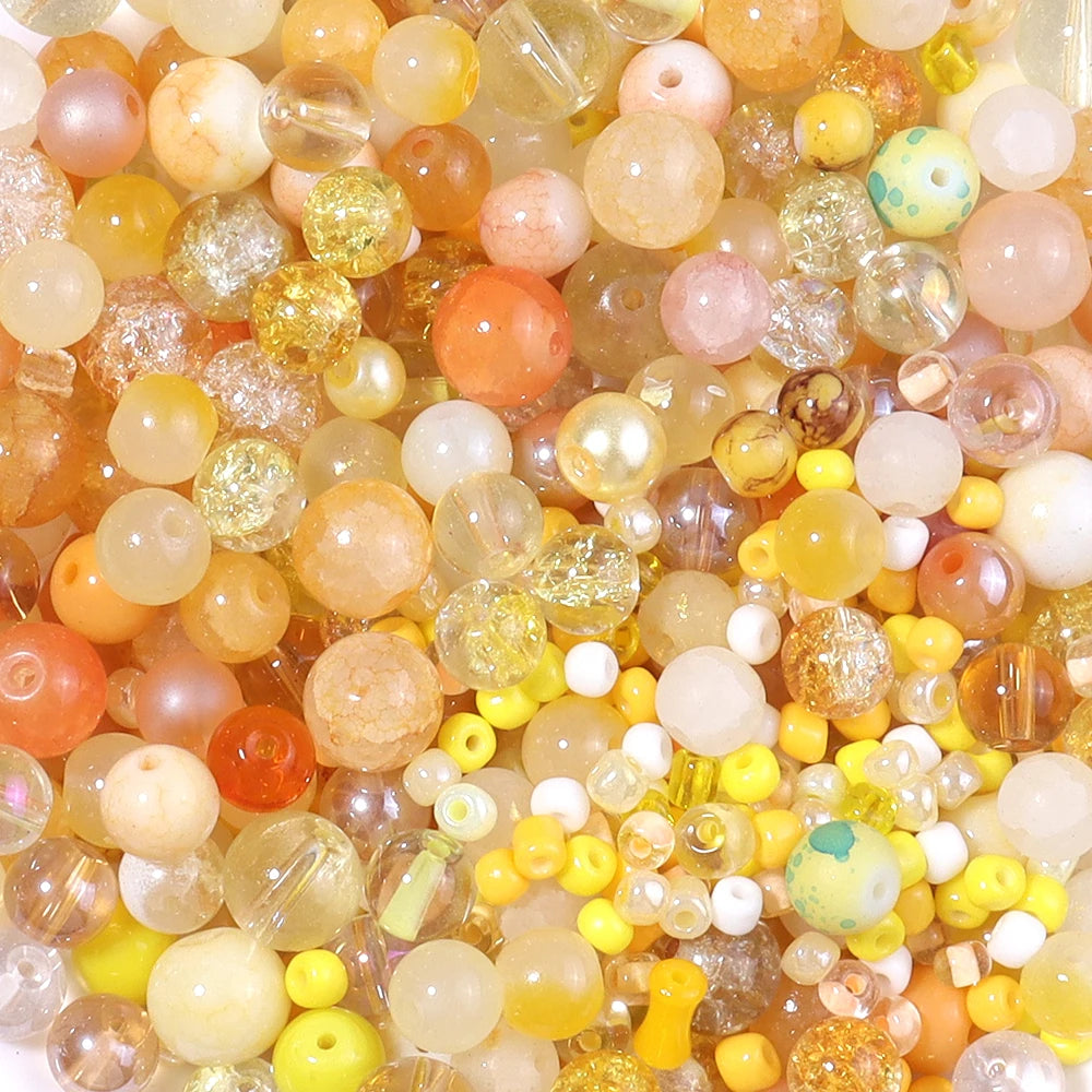 A close-up view of a vibrant mix of round glass beads in various shades including orange, yellow, pink, and clear.