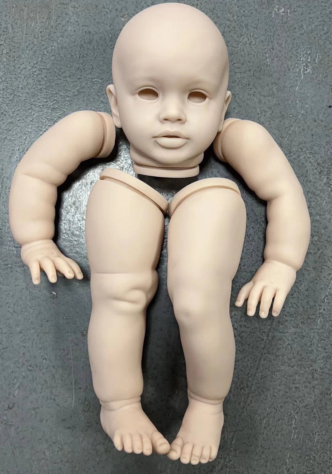 A realistic reborn baby doll kit of a nude infant with smooth skin and unpainted features.